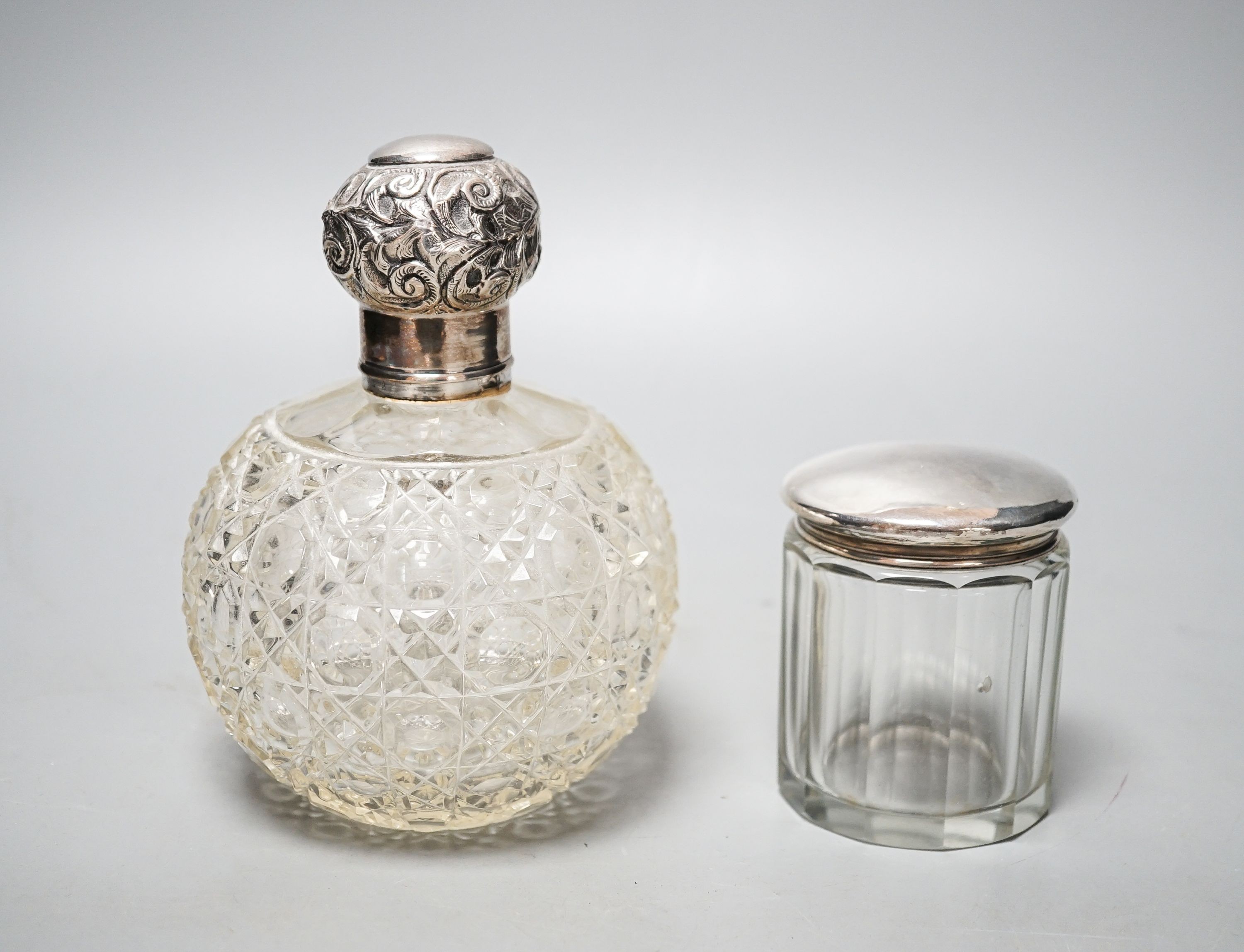 An Edwardian silver topped cut glass globular scent bottle, Birmingham, 1906, 15.3cm and a silver topped toilet bottle.